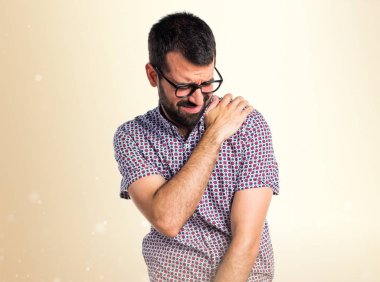 Koyu sarı arka plan üzerinde omuz ağrısı ile gözlüklü adam