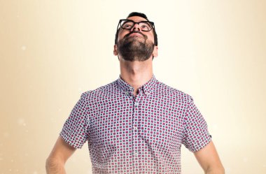 Koyu sarı zemin üzerine ararken gözlüklü adam