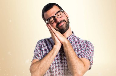 Koyu sarı arka plan üzerinde uyku jest yapıyor gözlüklü adam