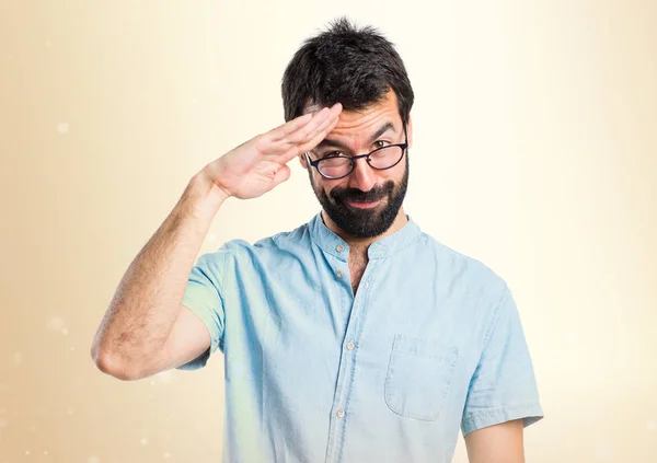 Schöner Mann salutiert auf ockerfarbenem Hintergrund — Stockfoto