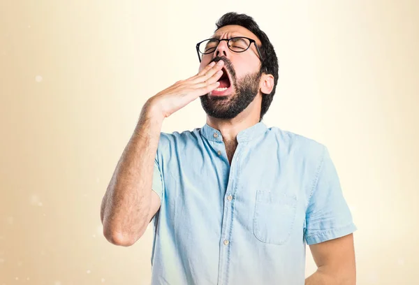 Schöner Mann gähnt auf ockerfarbenem Hintergrund — Stockfoto