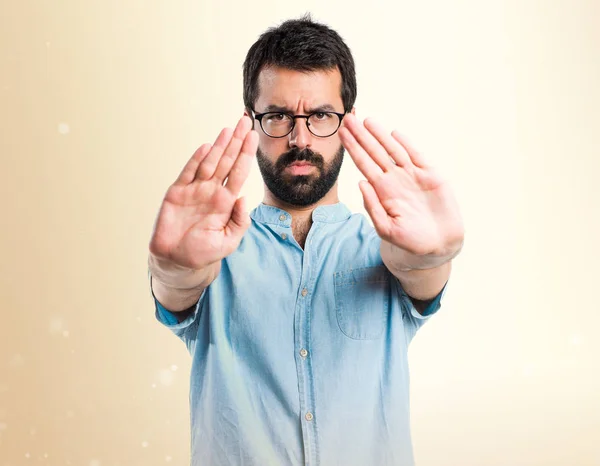 Schöner Mann macht Stoppschild auf ockerfarbenem Hintergrund — Stockfoto