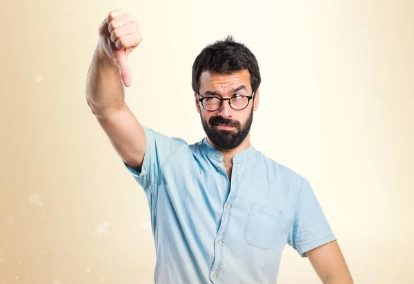 Pohledný muž s modrými brýlemi dělá špatný signál na okr backgro — Stock fotografie