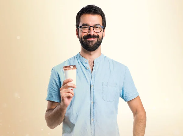 Schöner Mann mit blauer Brille trinkt Kaffee auf ockerfarbenem Hintergrund — Stockfoto
