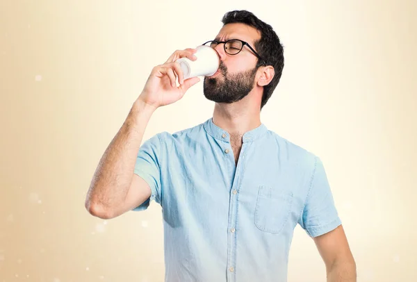 Pohledný muž s modrými brýlemi pití kávy na okrové poz — Stock fotografie