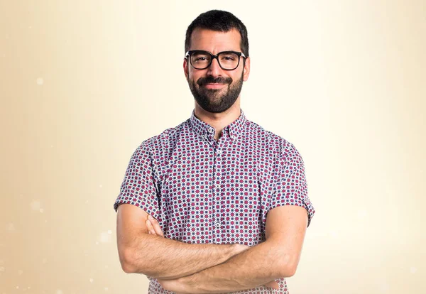 Hombre con gafas con los brazos cruzados sobre fondo ocre —  Fotos de Stock