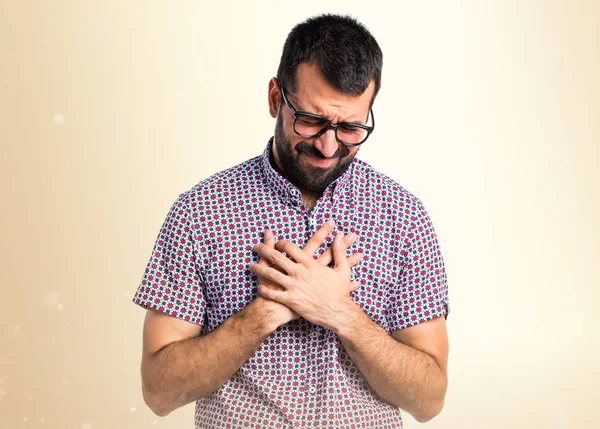 Hombre con gafas con dolor de corazón sobre fondo ocre —  Fotos de Stock