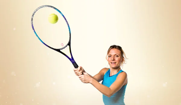 Mulher loira jogando tênis no fundo ocre — Fotografia de Stock