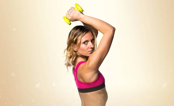 黄土色の背景に重量挙げを作るスポーツ女性 — ストック写真