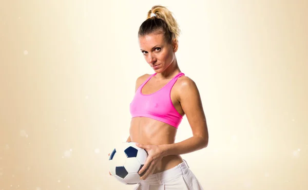 Vacker flicka footbal spelare på ockra bakgrund — Stockfoto