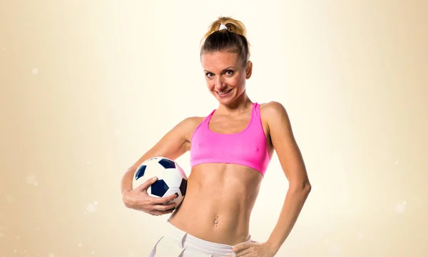 Schöne Fußballerin auf ockerfarbenem Hintergrund — Stockfoto