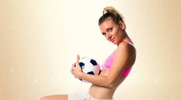 Hermosa chica futbolista sobre fondo ocre —  Fotos de Stock