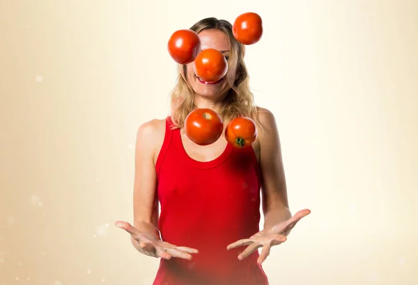 Hermosa mujer rubia sosteniendo tomates sobre fondo ocre — Foto de Stock