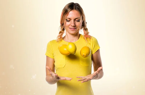 黄土色の背景にレモンを保持している美しい金髪女性 — ストック写真