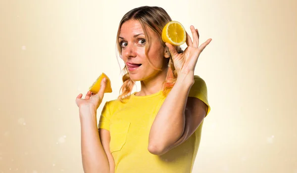 Limon koyu sarı arka plan üzerinde tutan güzel sarışın kadın — Stok fotoğraf