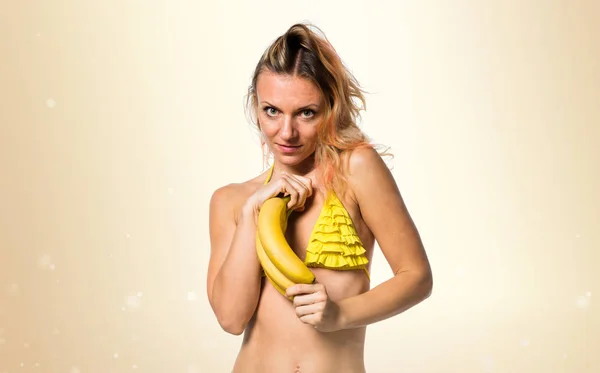 Mulher loira bonita de biquíni segurando bananas no ocre backgr — Fotografia de Stock