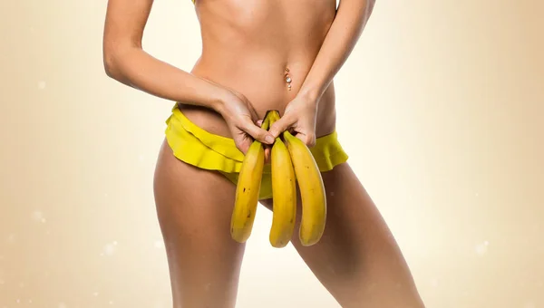 Блондинка в бикини, держащая бананы на бэкграунде — стоковое фото