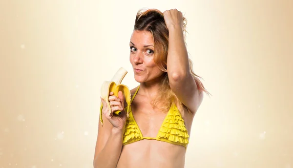 Piękna Blondynka w bikini, trzymając banany na tle ochry — Zdjęcie stockowe