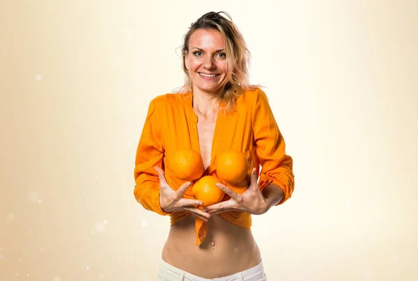 Bella donna bionda che tiene arance su sfondo ocra — Foto Stock