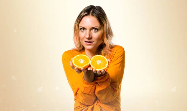Gyönyörű szőke nő gazdaság narancs okker háttér — Stock Fotó