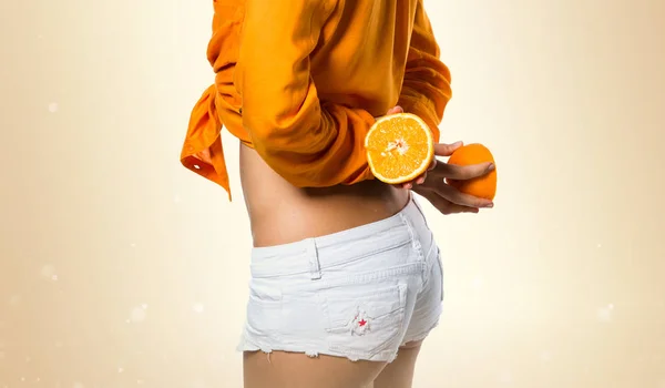 Bella donna bionda che tiene arance su sfondo ocra — Foto Stock