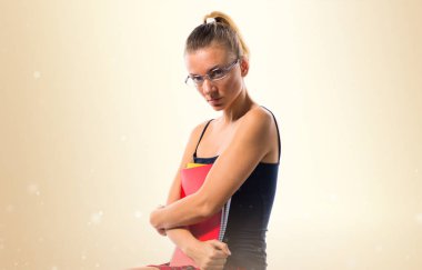 Pek çok kitap üzerinde oturan ve coll tutan güzel sarışın liseli kız