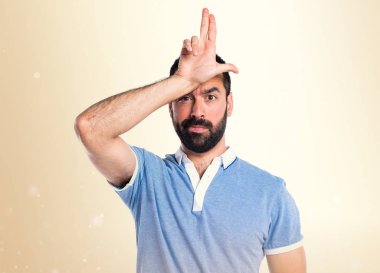 Adam mavi gömlek koyu sarı arka plan üzerinde aptal tabelayı yapıyor