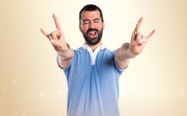 Adam koyu sarı zemin üzerine mavi gömlek yapma boynuz hareketi ile