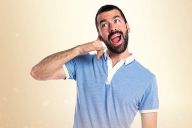 Adam koyu sarı zemin üzerine mavi gömlek yapma telefon hareketi ile