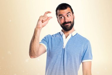 Adam mavi gömlek koyu sarı zemin üzerine küçük işareti yapıyor