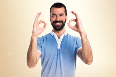 Adam mavi gömlek koyu sarı arka plan üzerinde oturum Tamam yapma ile