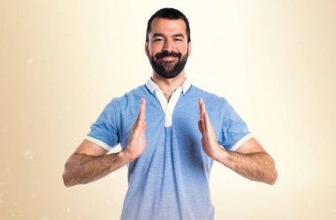 Bir şey Koyu sarı arka plan üzerinde tutan mavi gömlekli adam