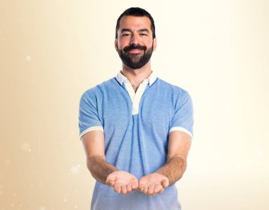 Bir şey Koyu sarı arka plan üzerinde tutan mavi gömlekli adam