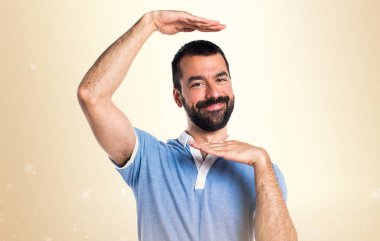 Bir şey Koyu sarı arka plan üzerinde tutan mavi gömlekli adam