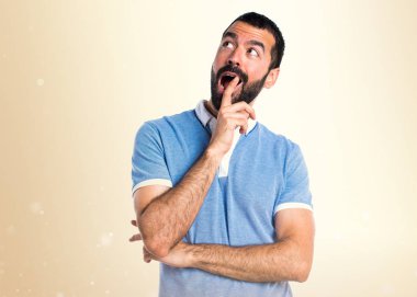 Adam mavi gömlek koyu sarı zemin üzerine sürpriz jest yapıyor