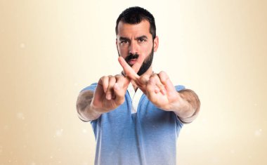 Adam mavi gömlek koyu sarı zemin üzerine bir jest yapıyor