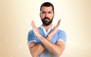 Adam mavi gömlek koyu sarı zemin üzerine bir jest yapıyor