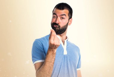 Adam mavi gömlek koyu sarı zemin üzerine para jest yapıyor