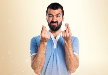 Adam mavi gömlek koyu sarı zemin üzerine para jest yapıyor