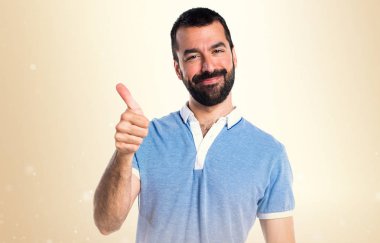 Adam koyu sarı zemin üzerine başparmak ile mavi gömlek ile