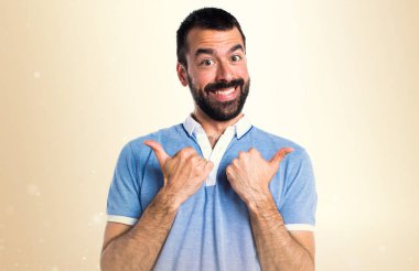 Adam koyu sarı zemin üzerine başparmak ile mavi gömlek ile