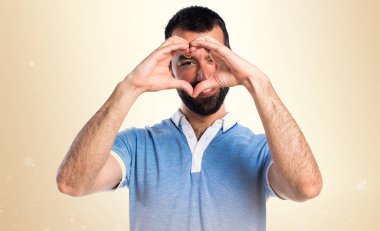 Adam mavi gömlek üzerinde koyu sarı backg elleri ile bir kalp yapma