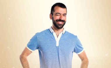 Mavi gömlek koyu sarı arka plan üzerinde göz kırpıyor ile adam