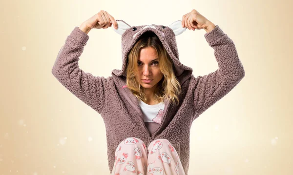 Hübsche blonde Mädchen im niedlichen Pyjama auf ockerfarbenem Hintergrund — Stockfoto