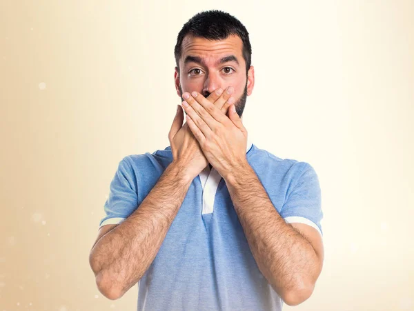 Man met blauwe shirt die betrekking hebben op zijn mond op okergeel achtergrond — Stockfoto