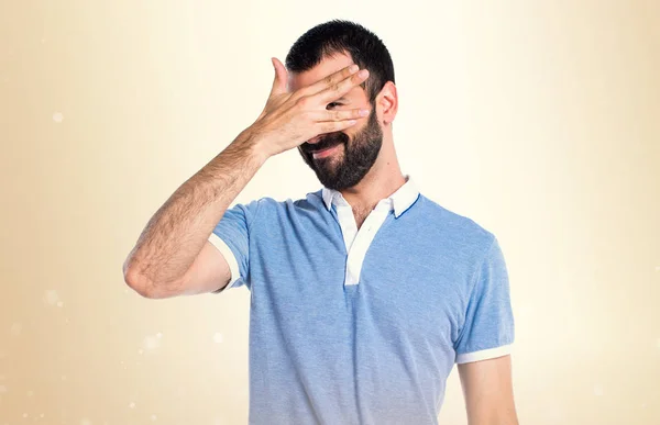 Άνδρας με μπλε πουκάμισο που καλύπτει το πρόσωπό του στο φόντο ώχρα — Φωτογραφία Αρχείου