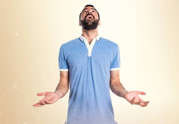 Hombre con camisa azul suplicando sobre fondo ocre —  Fotos de Stock