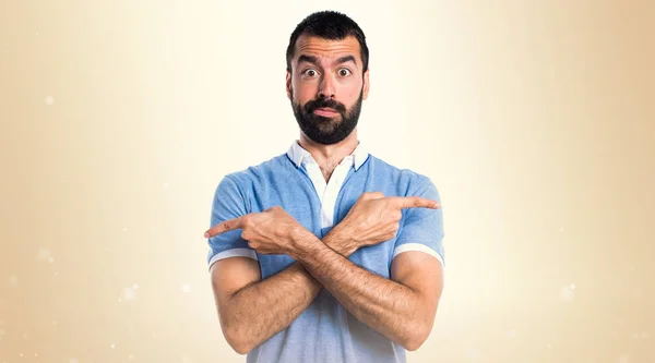 Homem com camisa azul apontando para as laterais tendo dúvidas sobre oc — Fotografia de Stock
