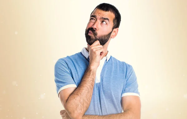 Mann mit blauem Hemd denkt auf ockerfarbenem Hintergrund — Stockfoto