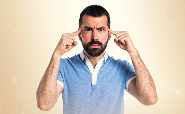 Mann mit blauem Hemd denkt auf ockerfarbenem Hintergrund — Stockfoto